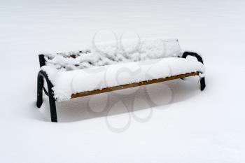 Wooden bench in deep snow after heavy snowfall