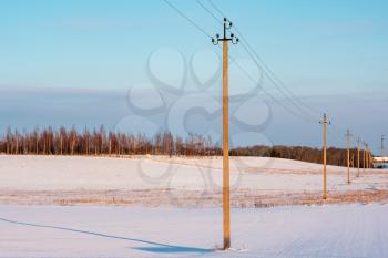 A wide angle view of Electricity Pylons crossing along a snowy field