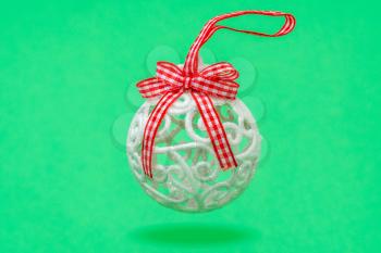 Decorative Christmas bauble with ribbon hanging over a green background.  Winter holiday decoration.