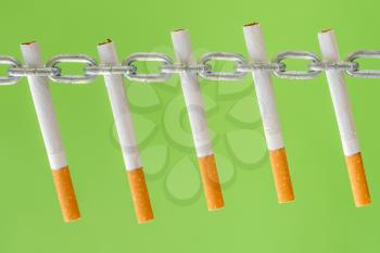 Cigarettes in a metal chain on green background, quit smoking - World No Tobacco Day 