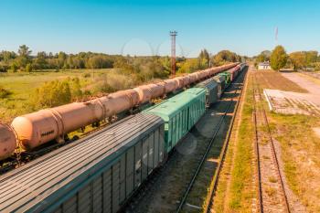 Wagons of a cargo train in motion. Scenic view of mixed freight train within rural landscape.