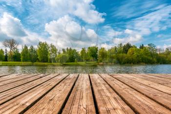 Idyllic view of the wooden pier in the lake with forest scenery background.
