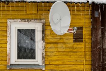 Satellite dish and window on the old wooden house 