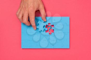 Man holding the final puzzle piece over a question mark. Concept of a problem and the solution.
