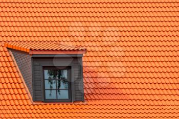 Renovated dormer window on the red house clay ceramic tiles roof