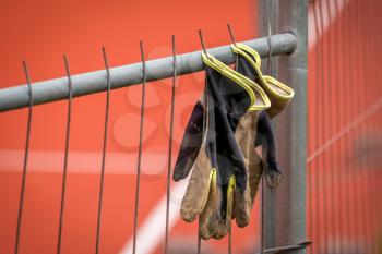Workers dirty gloves hanging on fence to dry, construction site