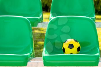 Soccer ball on the green seats of outdoor sports ground