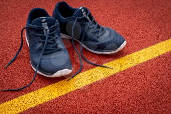 Running shoes are placed beside the start line on running track in the stadium.