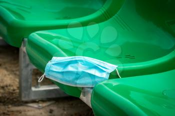 Medical protective mask on the green chairs of sports stadium. 