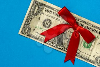 Dollar with decorative bow on blue background in closeup