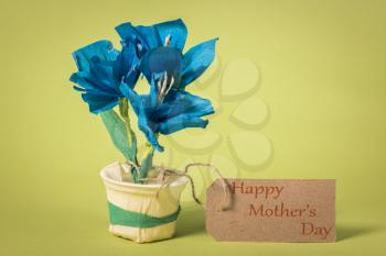 Children’s handicraft paper flowers, made of colorful paper. Greetings for Mom on Mother's Day with the inscription Happy mothers day.
