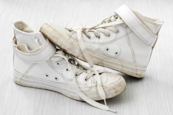 White dirty sneakers on white wooden background