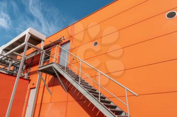 Iron staircase for up to maintenance work or fire escape. Steel stairs are on the side of the orange wall.