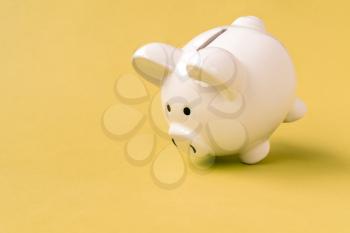 White ceramic piggy bank on yellow background. Copy space.