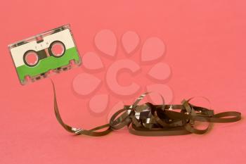 Cassette with pulled out tape on a pink background. Copy-space.