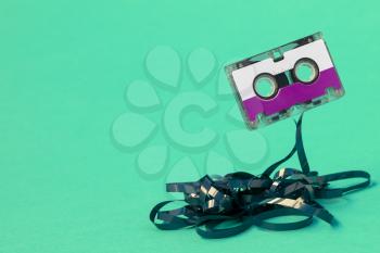Purple cassette with pulled out tape on a blue background
