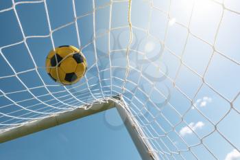 Soccer ball on the net of a football goals against blue sky