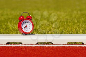 Red alarm clock on the running track in the stadium