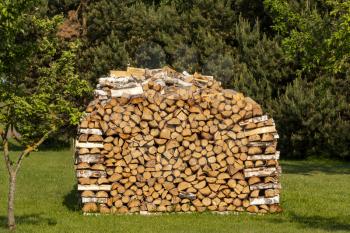 Stack of firewood getting dried on sunny summer day. Preparation of firewood for the winter. 