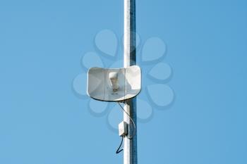 Wireless internet access point antenna on a street pole over a blue sky background