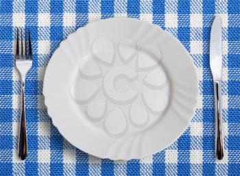 Lined white and blue dining cloth with plate and silverware