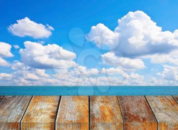 Wooden pier on sunny day with cloudy sky