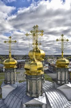 Golden domes of the Holy Trinity Cathedral in the background of the city, blue sky and white clouds (Verhoturie city of Sverdlovsk Region)