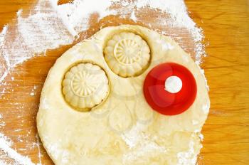 The dough for cookies with red tins strewn with flour on board