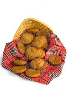 Oatmeal cookies on a red checkered napkin in a wicker basket isolated on a white background