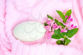White soap, a branch with pink flowers and green leaves on a pink towel