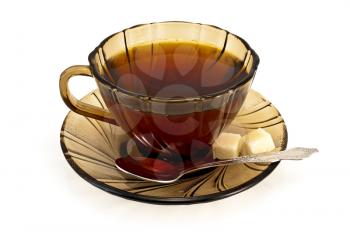 Tea in a brown glass cup with a spoon, two lumps of sugar isolated on white background
