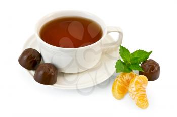 Tea in a white porcelain dish, three chocolates and two slices of mandarin, a sprig of green mint isolated on white background