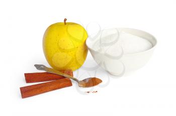 Yellow apple with a spoonful of ground cinnamon, two sticks whole cinnamon and sugar in a bowl is isolated on a white background