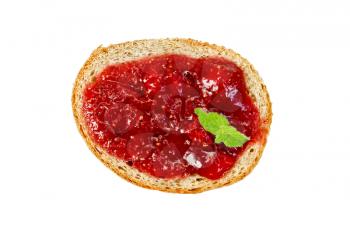Slice of french bread with strawberry jam and mint isolated on white background with a view from above