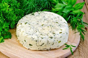 Homemade round cheese with herbs and spices on a wooden board
