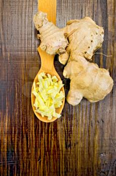 Wooden spoon with grated ginger, ginger root on a dark wooden board