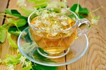 Herbal tea in a glass cup, fresh linden flowers on a background of wooden boards