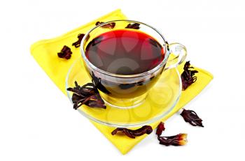 Hibiscus tea in a glass cup, dry petals tea on yellow napkin isolated on white background