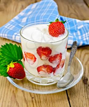 Thick yogurt with strawberries in a glass with a spoon on the saucer, napkin on a wooden board
