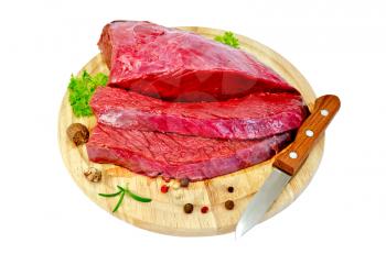 A piece of beef with spices and a knife on a round wooden board isolated on white background