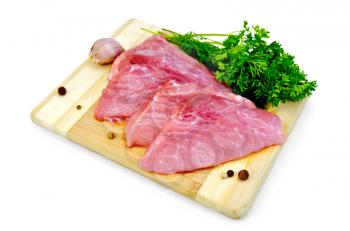 Two slices of pork, garlic, parsley, dill, pepper on a wooden board isolated on white background