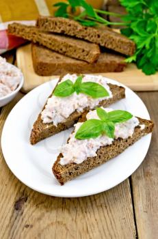 Sandwiches on two pieces of rye bread with cream of salmon and mayonnaise, basil, napkin, parsley on a wooden boards