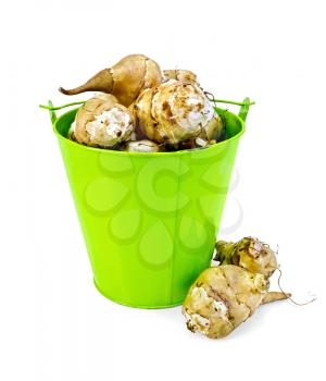 Pile of Jerusalem artichoke in a small green bucket and on the table isolated on white background
