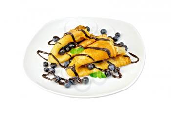 Two pancakes with blueberries, mint, chocolate icing on a white plate isolated on white background