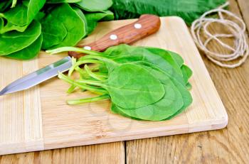 Green spinach, knife, twine, napkin on the background of wooden boards