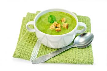 Green soup puree in a white bowl with croutons and spinach leaf on a napkin isolated on white background