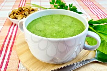Green soup puree in a bowl, spinach leaves, spoon derevyannoydoske, croutons on fabric background