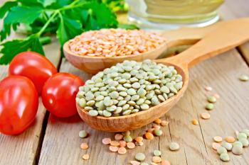 Red and green lentils in a wooden spoon, tomatoes, parsley, vegetable oil in a carafe on the background of wooden boards