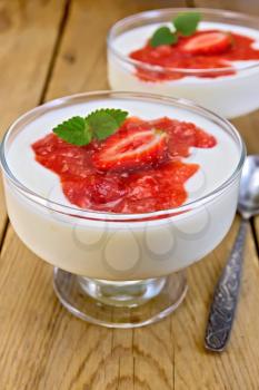 Two ice-cream bowls with a dessert of strawberries and yogurt, spoon on a background of wooden boards