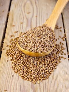 Buckwheat in a spoon on a wooden boards background